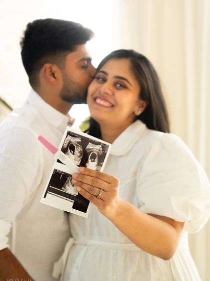 A joyful close-up of a couple celebrating their pregnancy news. The mom-to-be holds up her sonogram and a positive pregnancy test, her partner kissing her cheek in a moment of pure happiness.