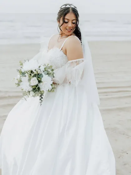 A stunning portrait of the bride on the beach. Her gown flows beautifully in the breeze, and her makeup is kept natural and radiant for this destination wedding.