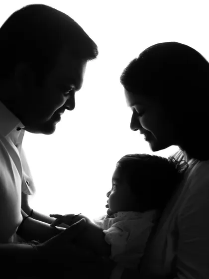 A timeless and artistic family portrait. This beautiful silhouette shot captures the intimate bond between new parents and their baby, focusing on connection and love in a simple, powerful way.