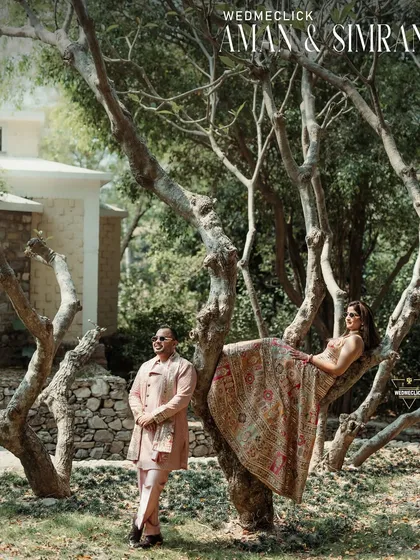 A creative and artistic portrait of the couple, with the bride perched in a tree, showcasing a fun and unique photo session.
