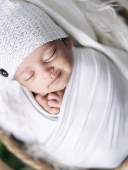 A smiling newborn, all wrapped up and cozy. Capturing a newborn's smile is a rare and precious moment that we always hope for.