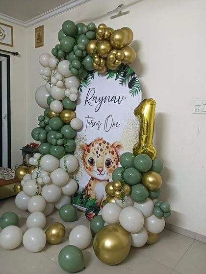 Another view of the jungle-themed first birthday decor, showing how the balloon garland elegantly frames the personalized backdrop for Raynav's celebration.