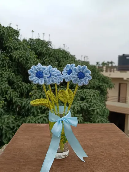 A small vase of blue daisy stems.