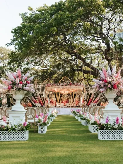The grand aisle leading to the Lotus Mandap, lined with large floral urns. This view showcases the complete journey from the guest seating to the sacred ceremony space.
