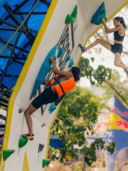 A climber in an orange life vest participates in the Psico Jam, a more relaxed format for fun, while another athlete scales the wall in a competitive setting.