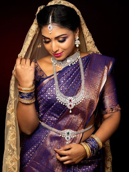 This close-up showcases a beautiful South Indian bridal makeup look. The focus is on the eyes, with a purple smokey effect and perfectly defined brows, paired with diamond jewellery.