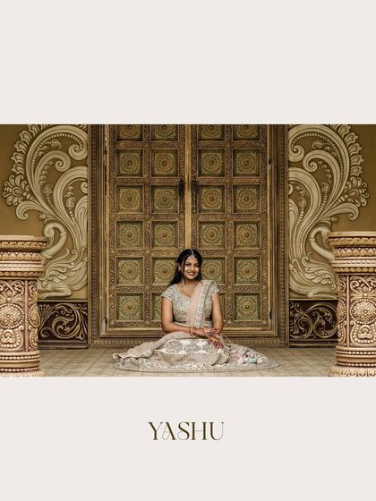A beautiful portrait of the bride, Yashu, seated before a massive, intricately carved door, looking like royalty.