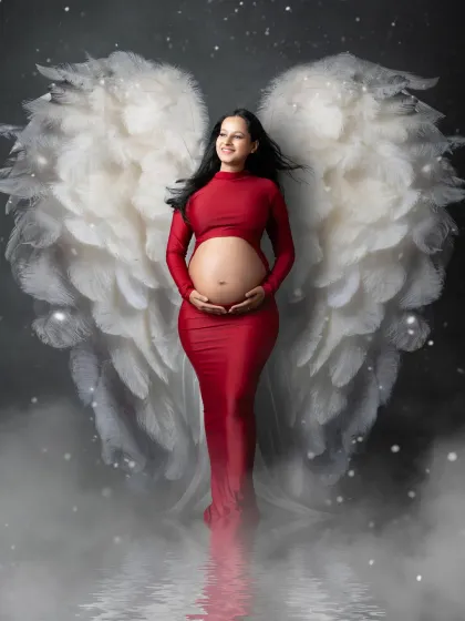 A portrait that feels as magical as the moment itself. We styled this mother-to-be in a striking red gown with ethereal angel wings, using a misty, reflective floor to create a heavenly atmosphere. This is an example of our creative, fine-art approach to maternity photography.