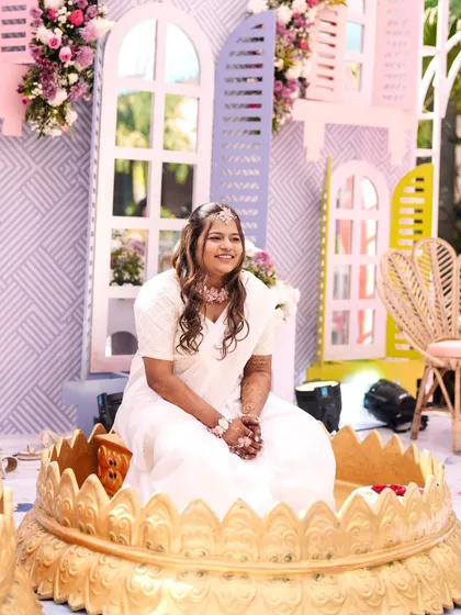 A beautiful bride seated for her wedding ceremony, looking serene and radiant in her white and pink attire.