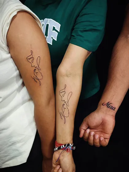 This photo shows a family who got tattooed together. It features two continuous line face tattoos and a 'Maa' script tattoo, celebrating their shared bond.