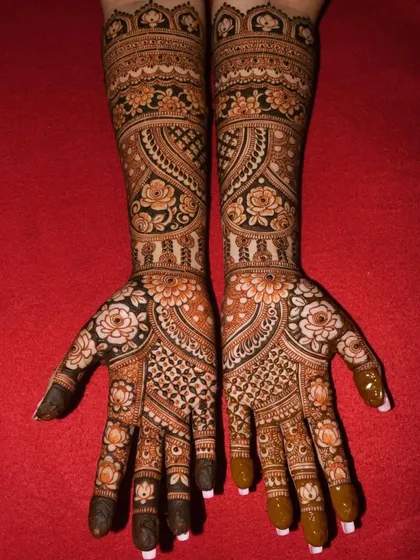 A beautiful example of full-coverage floral mehandi. The design uses a mix of bold flowers and delicate vines to cover the hands and arms completely.