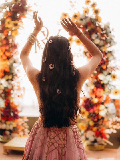A beautiful shot from behind, showing the bride's long hair decorated with flowers against a floral arch. This highlights the beauty of her hair and the decor.