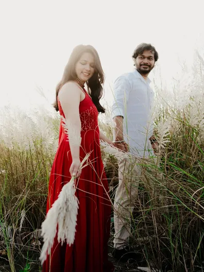 A candid shot of the couple walking through a field. The bride leading the groom creates a playful and interactive dynamic.