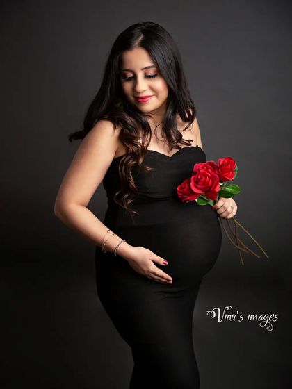 Simple, classic, and beautiful. A solo portrait of the mother-to-be in a simple black gown, holding red roses that add a pop of color and romance.