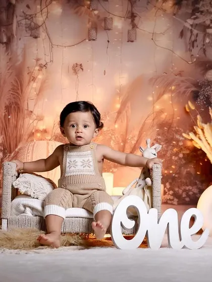 A confident pose from the birthday boy in our warm, candle-lit boho setup, sitting on a miniature bed.