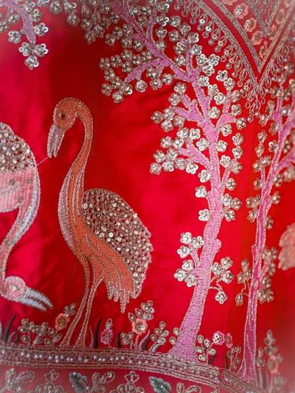 A close-up of the stunning and unique flamingo embroidery on a bridal lehenga. Capturing these small, personal details is part of telling the complete story of your wedding style.