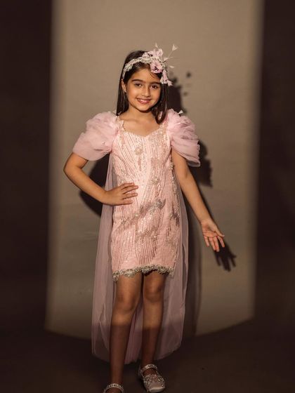 This pretty pink dress features puffy sleeves, a sequined body, and a sheer, detachable tail.