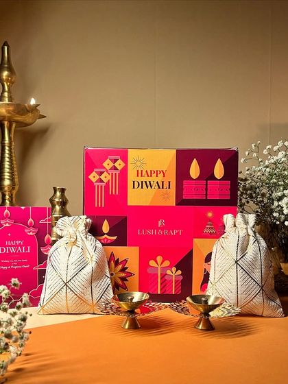 Illuminate your celebrations with this vibrant Diwali gift set, featuring decorative pouches and brass diyas in a colorful "Happy Diwali" box.