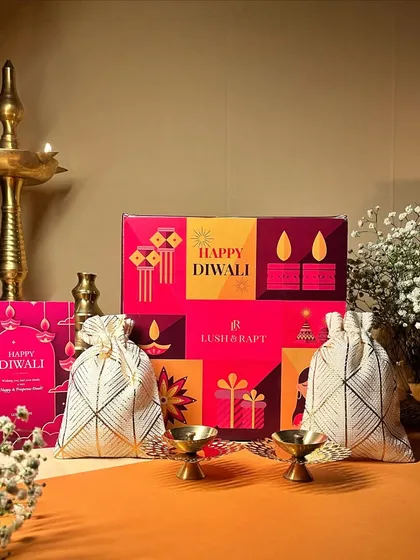 This bright and cheerful Diwali gift set includes a 'Happy Diwali' box, matching card, and two potlis filled with treats, perfect for sharing joy with loved ones.