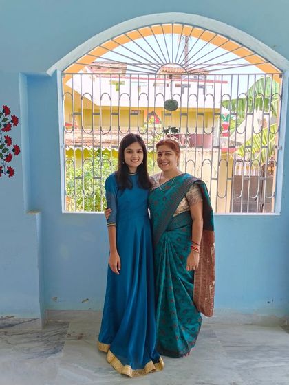 A photo of my mother and me standing proudly in front of the completed floral pillar mural at our home.
