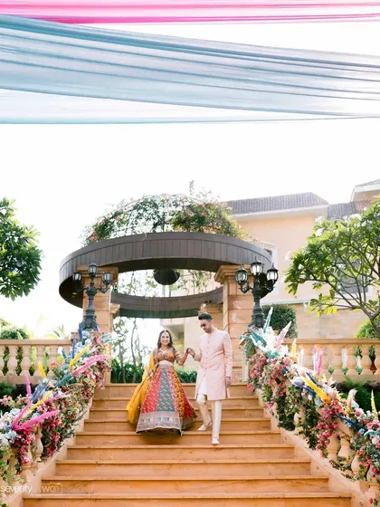 The couple makes their grand entrance down a beautifully decorated staircase for their Mehendi ceremony at Della Resorts, Lonavala.