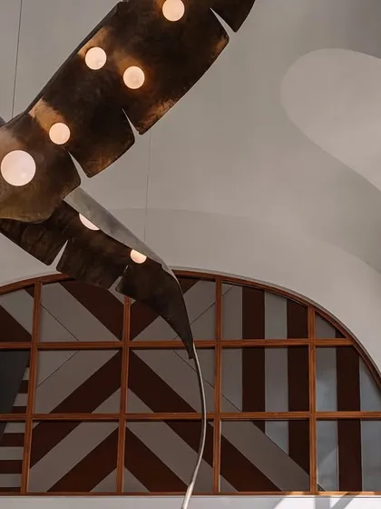 Lighting can be the jewelry of a space. In this double-height living room, we collaborated with artists to create this dramatic installation of oversized, illuminated metal fronds. The piece fills the grotto-inspired ceiling, casting a warm glow and acting as a magnificent sculptural focal point.