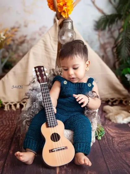 Strumming his first guitar. I have lots of fun, baby-safe props like this mini ukulele to make the photoshoot interactive and capture genuine moments of play.