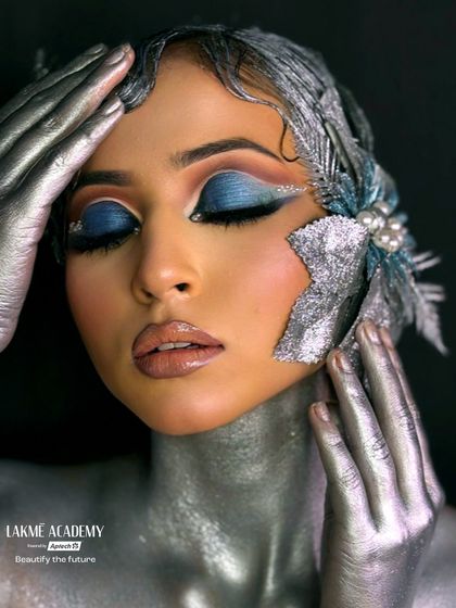 Another angle of this stunning creative makeup, showing the careful placement of facial adornments and the blend of cool and warm tones. We encourage our students to experiment and develop their unique artistic style.