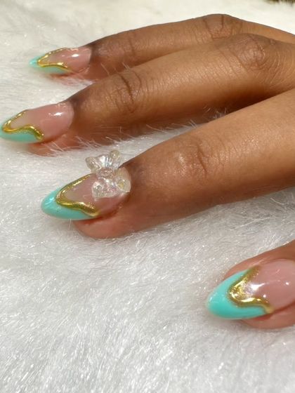A close-up of a delicate and elegant 3D design. This look features a turquoise and gold outline design with a clear, sculpted 3D bow on the accent nail.
