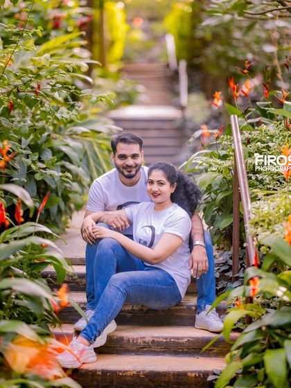 A relaxed and casual couple's portrait on a staircase surrounded by greenery.