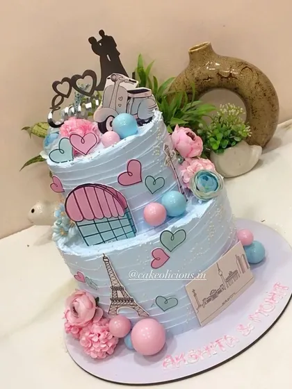 This thoughtful two-tier engagement cake tells the couple's story, depicting their journey of togetherness across Paris and Berlin. It's decorated with edible prints of the Eiffel Tower, hearts, and a scooter for a truly personal touch.