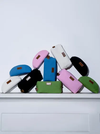 A vibrant pile of multi-colored pouches against a clean white background. This shot is a simple but effective way to showcase the full range of colors available for a product.