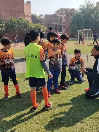 A coach kneels down to his players' level to discuss tactics. We believe in clear communication and mutual respect.