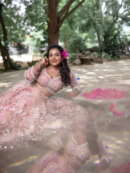 A creative shot with a reflection, showcasing the model's beautiful pink lehenga and subtle makeup.