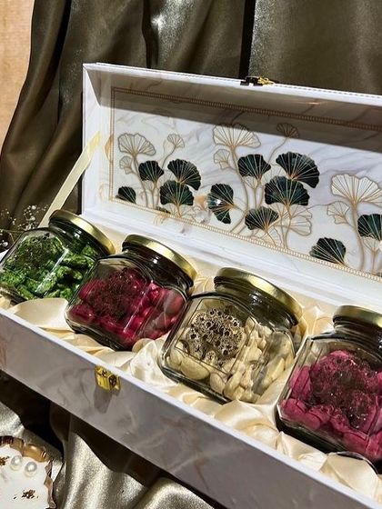 A luxurious marble-finish box for Diwali, containing four glass jars filled with premium dry fruits and coated nuts.
