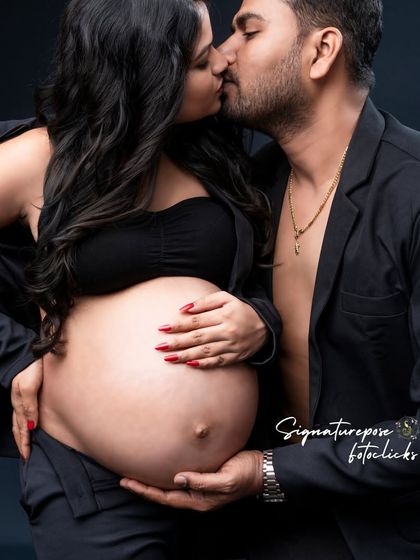 An intimate and modern couple's portrait, sharing a kiss while cradling the bump. A truly powerful image of partnership.