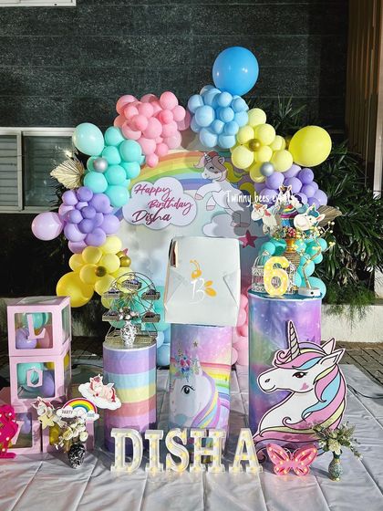 A pastel rainbow unicorn theme for Disha's 6th birthday. This magical setup features a unicorn and rainbow backdrop, themed pedestals, and colorful balloon clouds for a dreamy party.