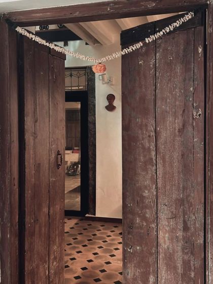 Even the simplest traditions bring a space to life. A marigold garland hangs over a restored wooden door, a small celebration of the everyday. It’s these human touches that turn a building into a home.