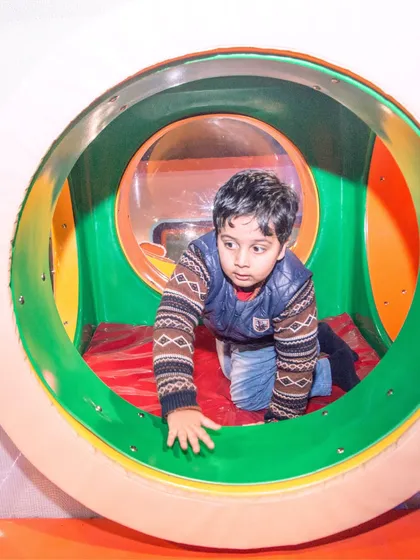 A young explorer crawling through one of the many colorful tunnels that connect different parts of the My Maze structure.
