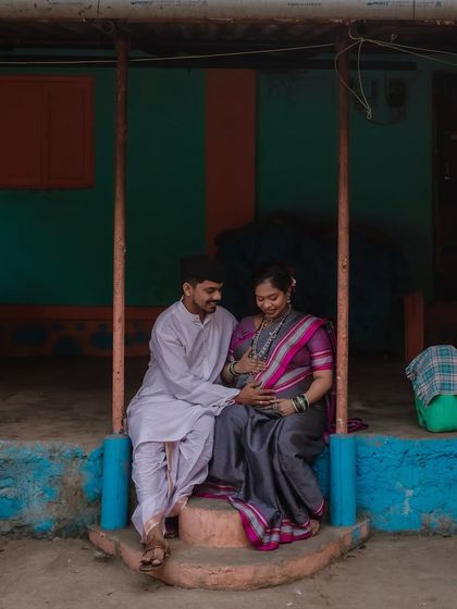 A tender moment as he places his hand on her belly. The setting of the village home adds a layer of warmth and authenticity to their story.