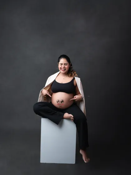 A playful and personal touch! This fun portrait captures the mother-to-be's joyful personality, with cute smiley faces drawn on her baby bump.