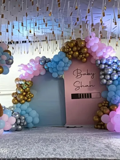A "Baby Shah" gender reveal party with a loading bar graphic. The mix of pink, blue, silver, and gold balloons builds anticipation, while the teddy bear and 'BABY' blocks add a cute touch.