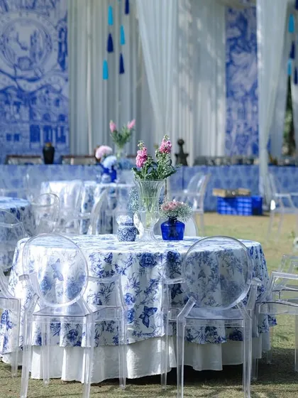 The dining area for the blue and white themed event, with tables dressed in Mediterranean-style printed cloths and paired with modern transparent ghost chairs.