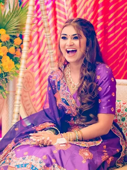 A joyful bride with her beautiful half-up braided hairstyle, perfect for a colorful mehendi or sangeet ceremony.