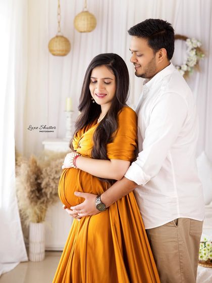 A classic pose by the window, with the husband gently holding the baby bump. The soft, natural light creates a warm and intimate atmosphere.