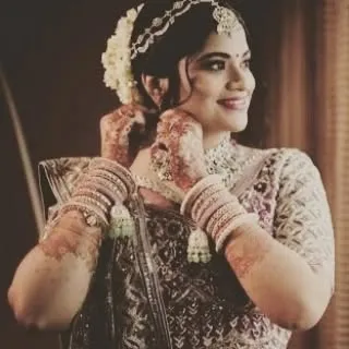 The bride adjusting her earrings, showcasing her complete look with intricate jewelry and a classic updo adorned with flowers.