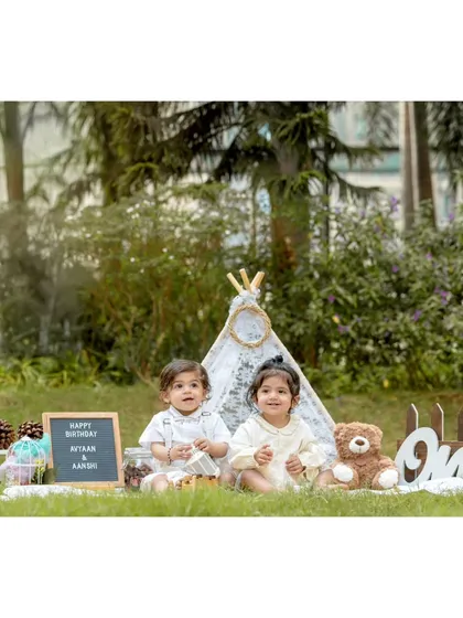 This pre-birthday shoot for twins Avyaan and Aanshi shows a complete themed setup in an outdoor park. I provide all the props, including the teepee, signage, and teddy bear, to create a magical setting for your child's milestone photos.