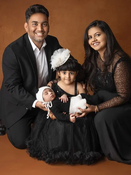 There is nothing more beautiful than a family coming together to celebrate a new life. This is a full family portrait, with everyone dressed in coordinated black outfits, creating a timeless and elegant memory.