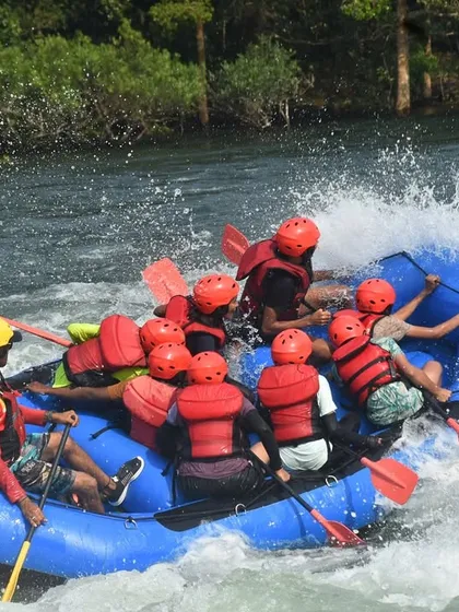 An overhead view shows a raft full of participants working together, paddles in the water, as they navigate a tricky section of the river.
