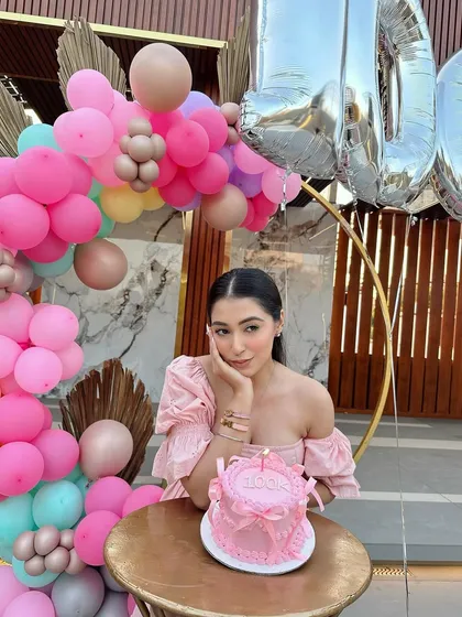 A quiet moment of reflection amidst the celebration. The soft colors of the balloons and the elegant cake create a picture-perfect scene.